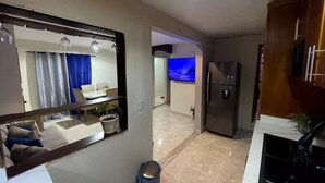 Una cocina moderna con refrigerador, lavamanos y comedor con mesa y sillas.