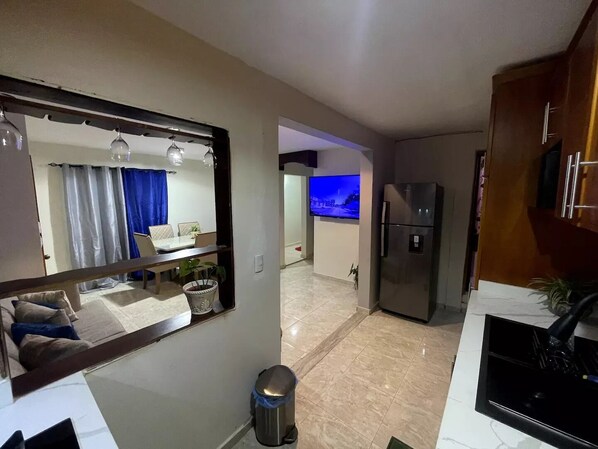 A modern kitchen with a refrigerator, a sink, and a dining area with a table and chairs.