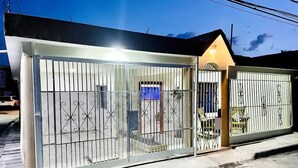 Una propiedad amurallada con cerca de metal y un pequeño edificio con tejado inclinado.