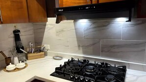 Una cocina con estufa negra, armarios de madera y salpicadero de mármol.