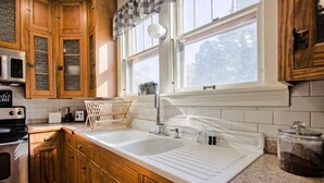Una cocina con armarios de madera, un lavamanos doble y una ventana sobre el lavamanos.