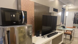 Une cuisine moderne équipée d’un réfrigérateur en acier inoxydable, d’un four à micro-ondes, d’un téléviseur à écran plat et d’une table à manger en verre.