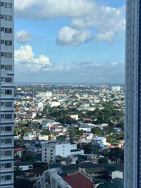 Un paysage urbain composé d’un mélange de bâtiments résidentiels et commerciaux, avec un ciel dégagé et quelques nuages.