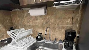 A kitchen with a stainless steel sink, a coffee maker, and a dish rack. - Pretty & Modern Private Studio 202 (Cali)