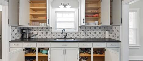 A kitchen with white cabinets, a black countertop, and a tiled backsplash.