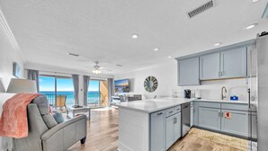 A modern kitchen with grey cabinets, a central island, and a view of the ocean.
