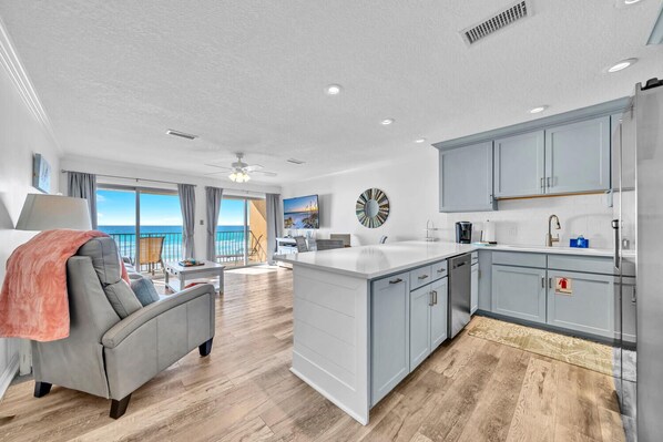 A modern kitchen with grey cabinets, a central island, and a view of the ocean.