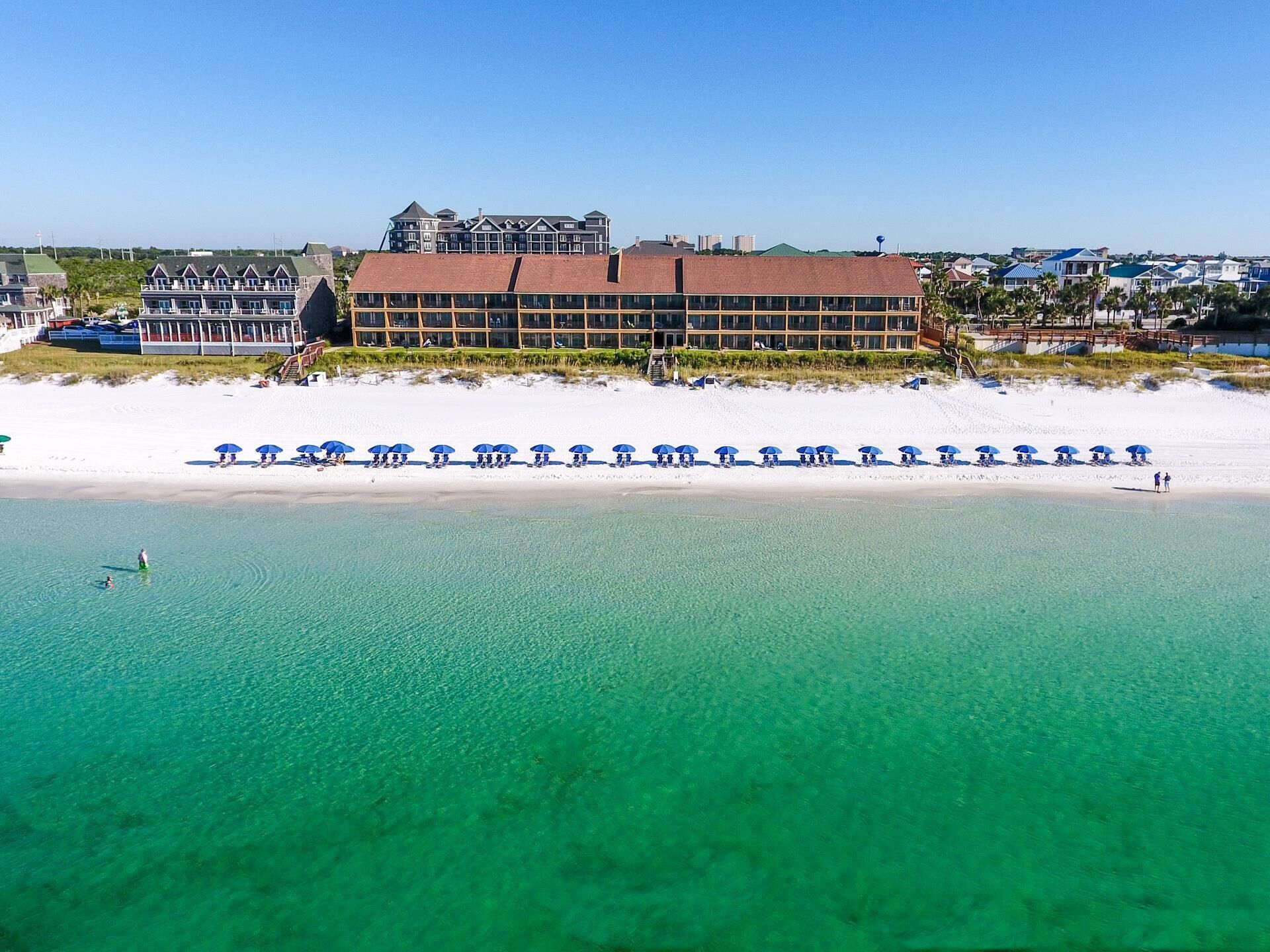 Ein Strandhotel mit einer Reihe von Strandsonnenschirmen und einem mehrstöckigen Gebäude.