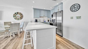 A modern kitchen with a central island, stainless steel appliances, and light blue cabinetry.