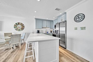 A modern kitchen with a central island, stainless steel appliances, and light blue cabinetry.