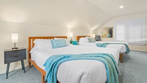 A bedroom with two beds, a nightstand, and a wall-mounted lamp.