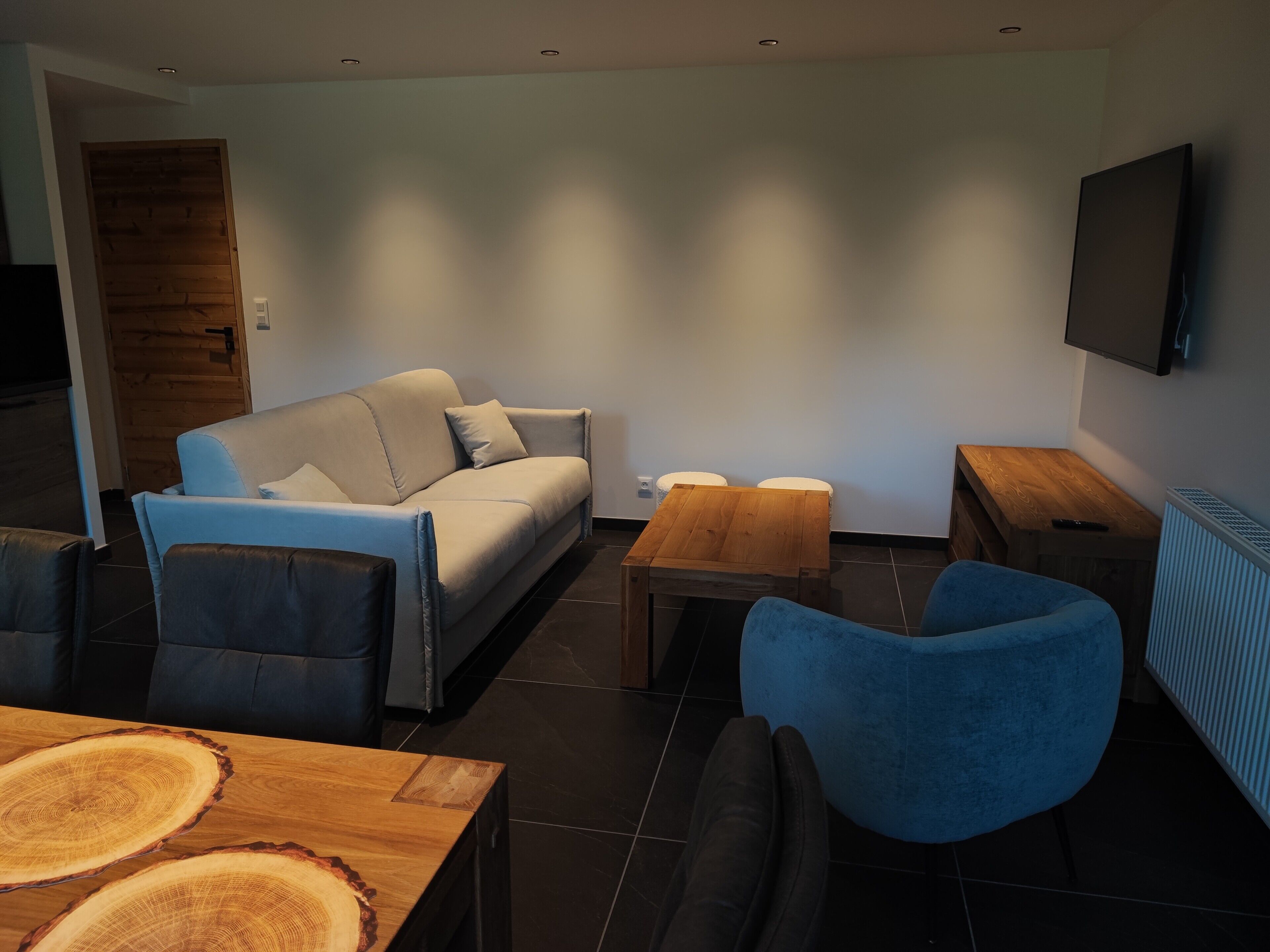 A modern living room with a sofa, a coffee table, and a TV mounted on the wall.