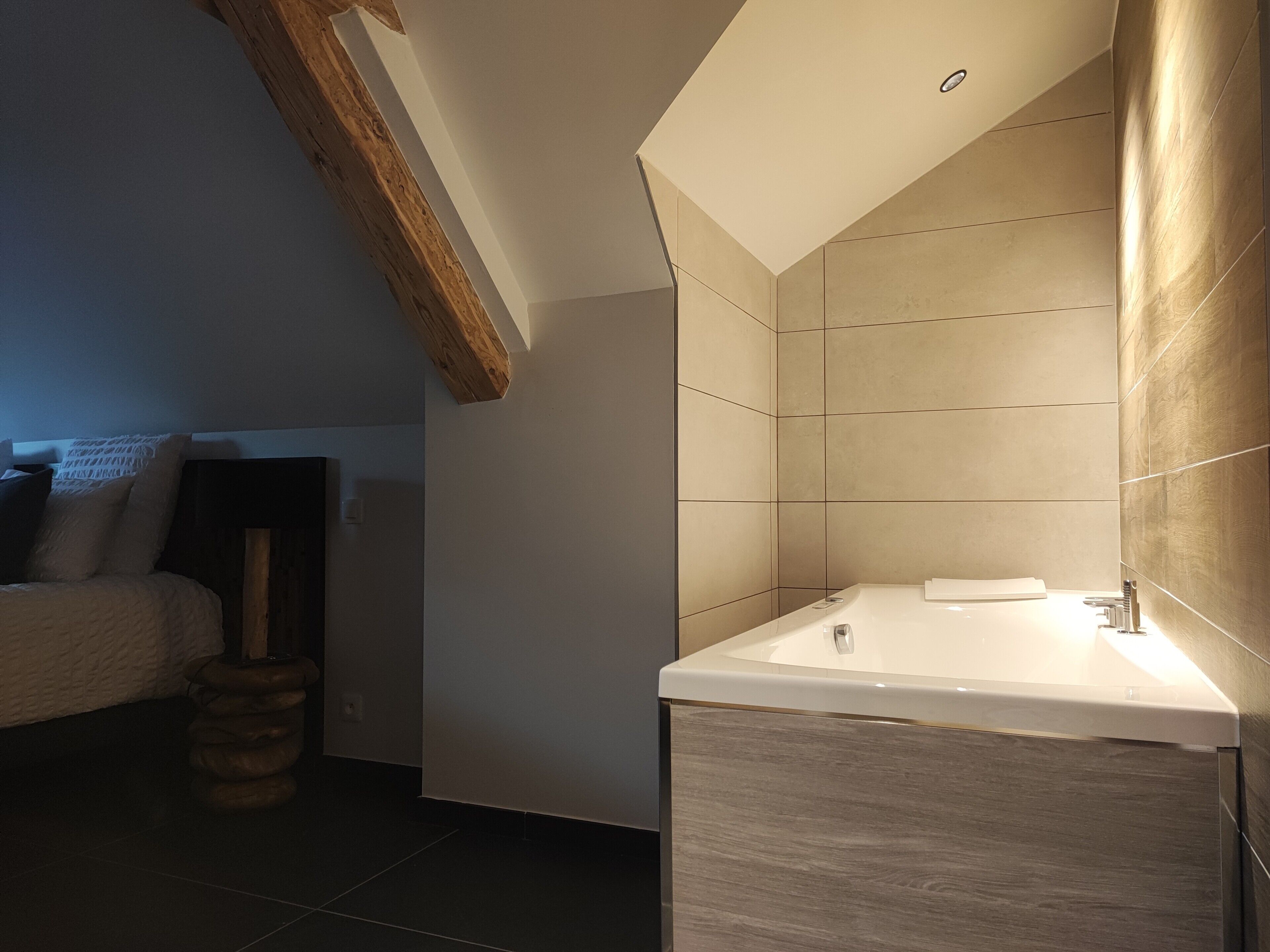 Une salle de bain moderne avec un grand lavabo, des murs carrelés et un plafond en pente.