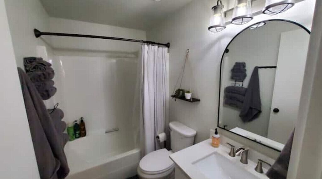 Ein Badezimmer mit Dusche, Toilette, Waschbecken und Spiegel.