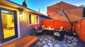 A patio with stone flooring, a wooden bench, and a table with chairs.