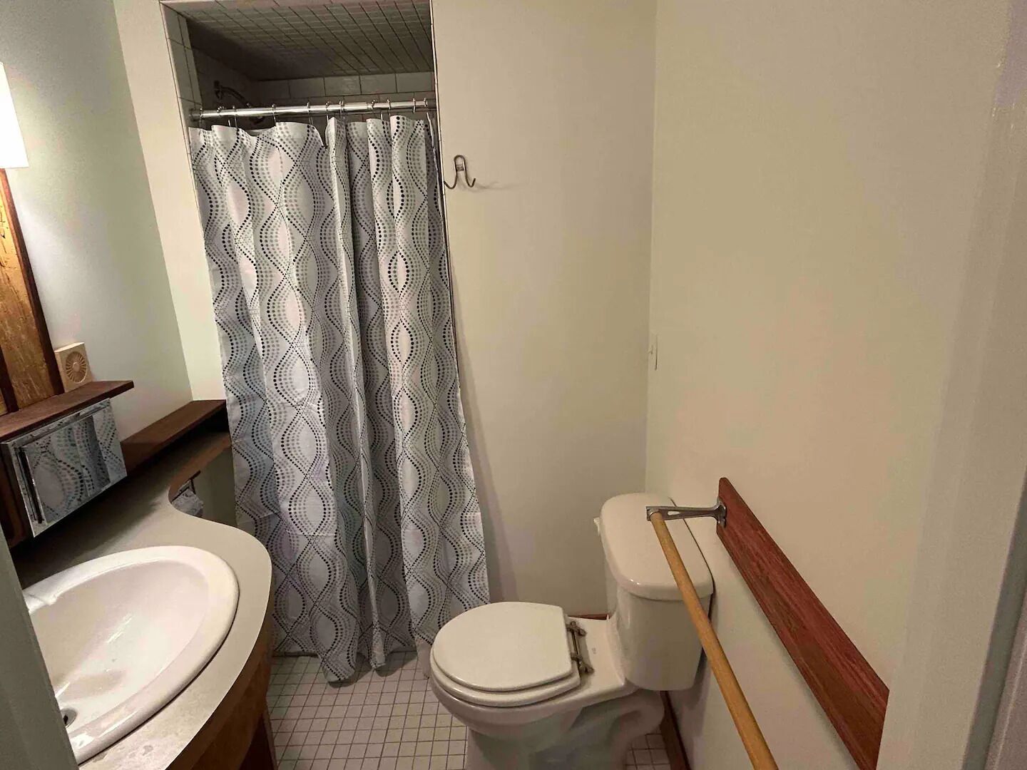 A bathroom with a white toilet, a sink, and a shower curtain with a geometric pattern.