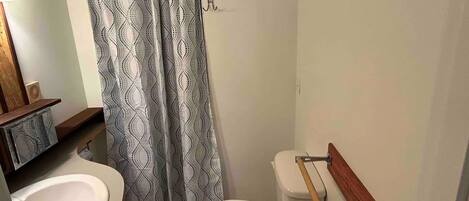 A bathroom with a white toilet, a sink, and a shower curtain with a geometric pattern.