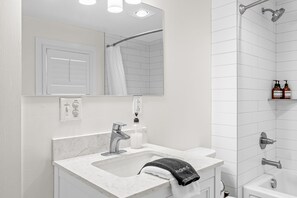 Un baño moderno con un lavamanos blanco, un espejo, una ducha y un perchero para toallas.