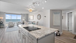 Una cucina moderna con un'isola grande, un'area pranzo con sedie e vista sull'oceano.