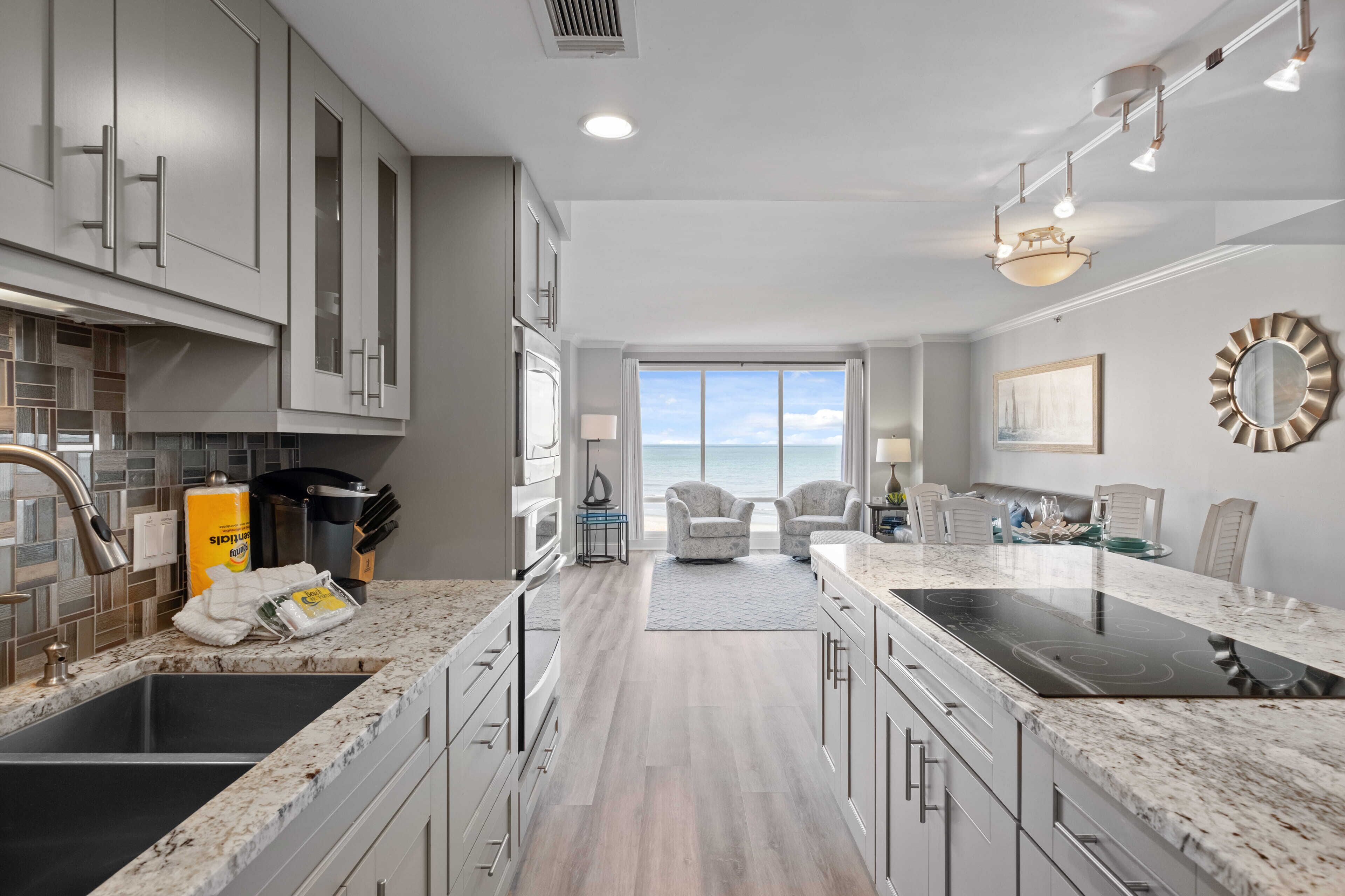 A modern kitchen with a large island, built-in appliances, and a view to the outside.