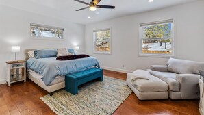 A bedroom with a bed, a blue bench, a sofa, and a ceiling fan.