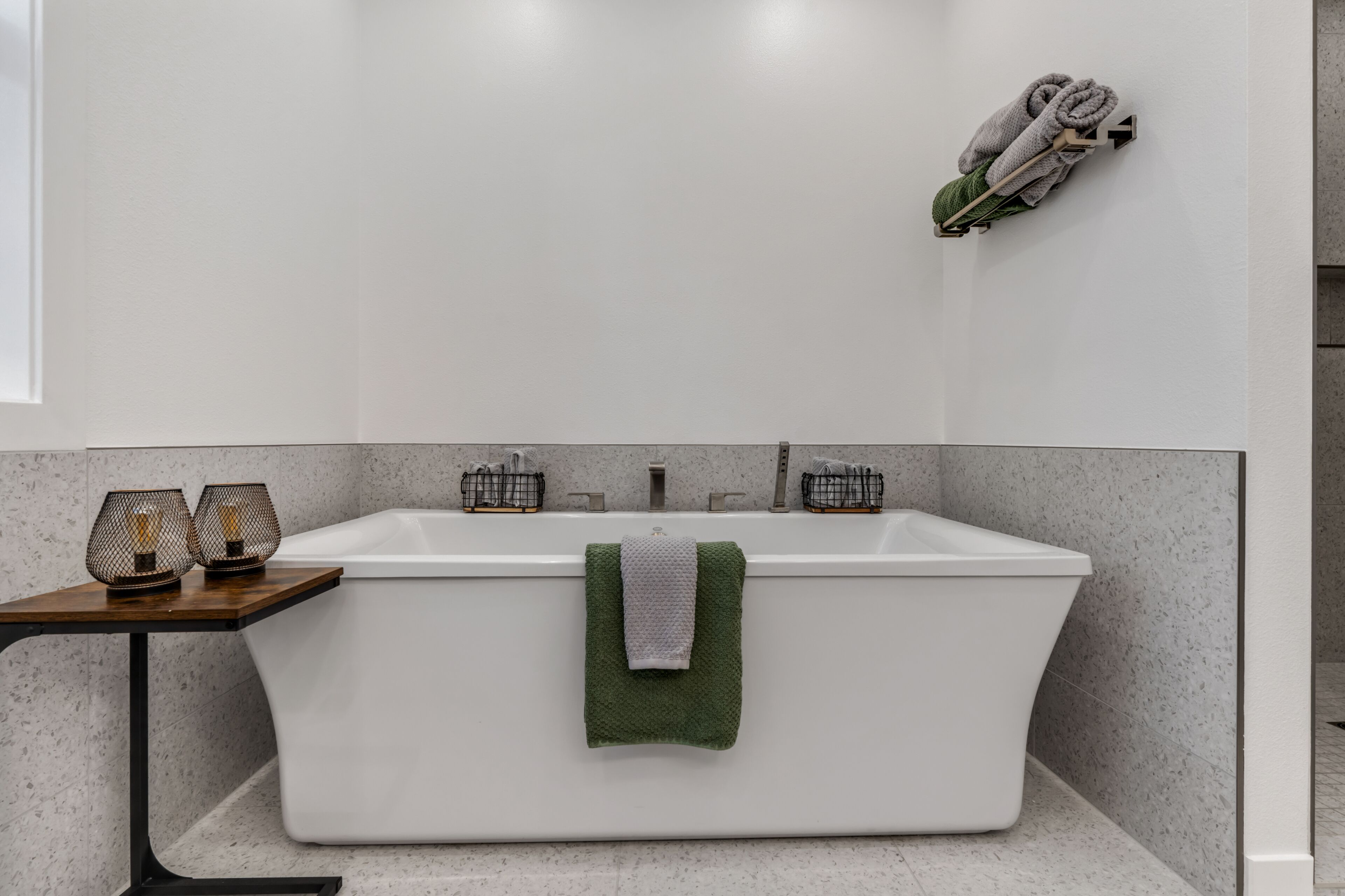 Une salle de bain moderne avec une baignoire sur pieds, une petite table avec deux bougies et un porte-serviettes avec des serviettes.