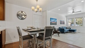 A spacious living area with a dining table, chairs, a sofa, and a large window with a view.