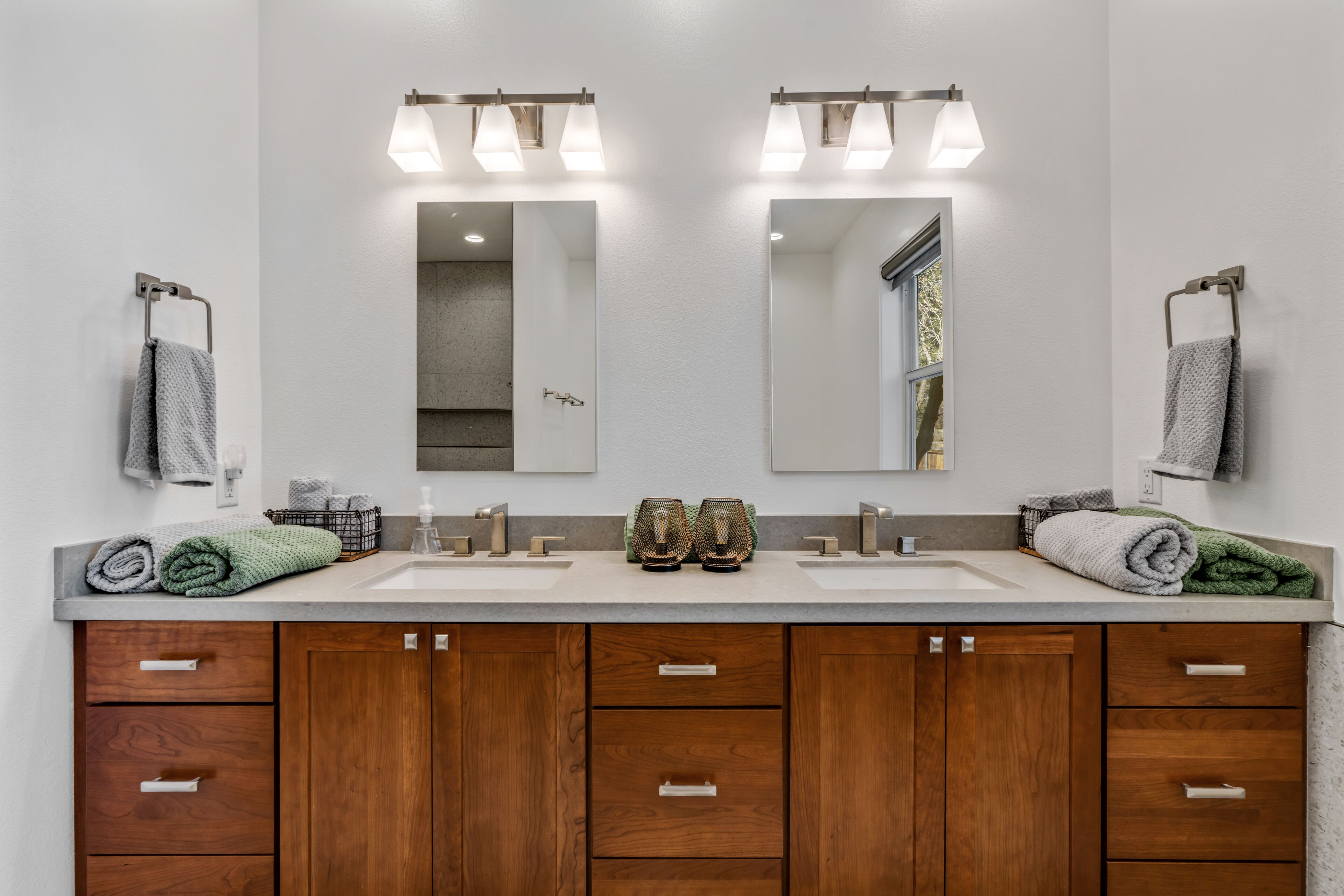 A bathroom with two sinks, wooden cabinets, and a large mirror.