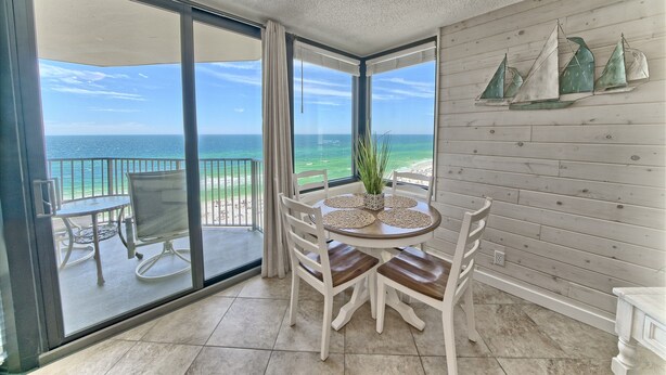 Ein Balkon mit Blick auf das Meer, ein Esstisch mit Stühlen und ein Blumentopf.