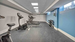 A gym with treadmills, stationary bikes, and a rack of dumbbells.