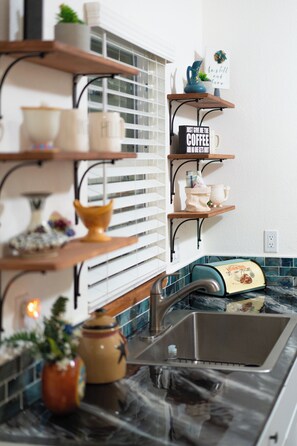 Una cocina con estantes de madera, una taza de café y un tostador.