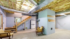 Un sous-sol avec une isolation apparente, un escalier, une chaise et un banc en bois.