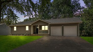 A two-story house with a front porch, two garage doors, and a well-maintained lawn. - Stylish Rancher in Quiet, Tree Lined Neighborhood. (Joplin)