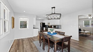 A modern kitchen with white cabinets, a wooden dining table, and a chandelier. - Stylish Rancher in Quiet, Tree Lined Neighborhood. (Joplin)