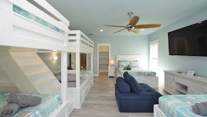 Ein Schlafzimmer mit Etagenbetten, einer Schlafcouch, einem Fernseher und einem Deckenventilator.