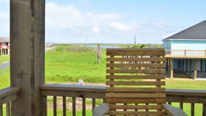 Eine Holzterrasse mit Blick auf eine Wiese und ein Gebäude im Hintergrund.