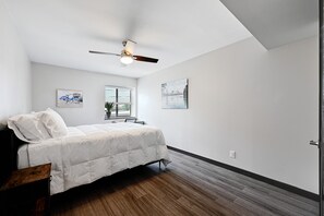 A bedroom with a bed, a ceiling fan, a window with blinds, and two wall-mounted artworks. -  North Campus (UT-Austin) Apt 7 /Red River/Moody Center (Austin)