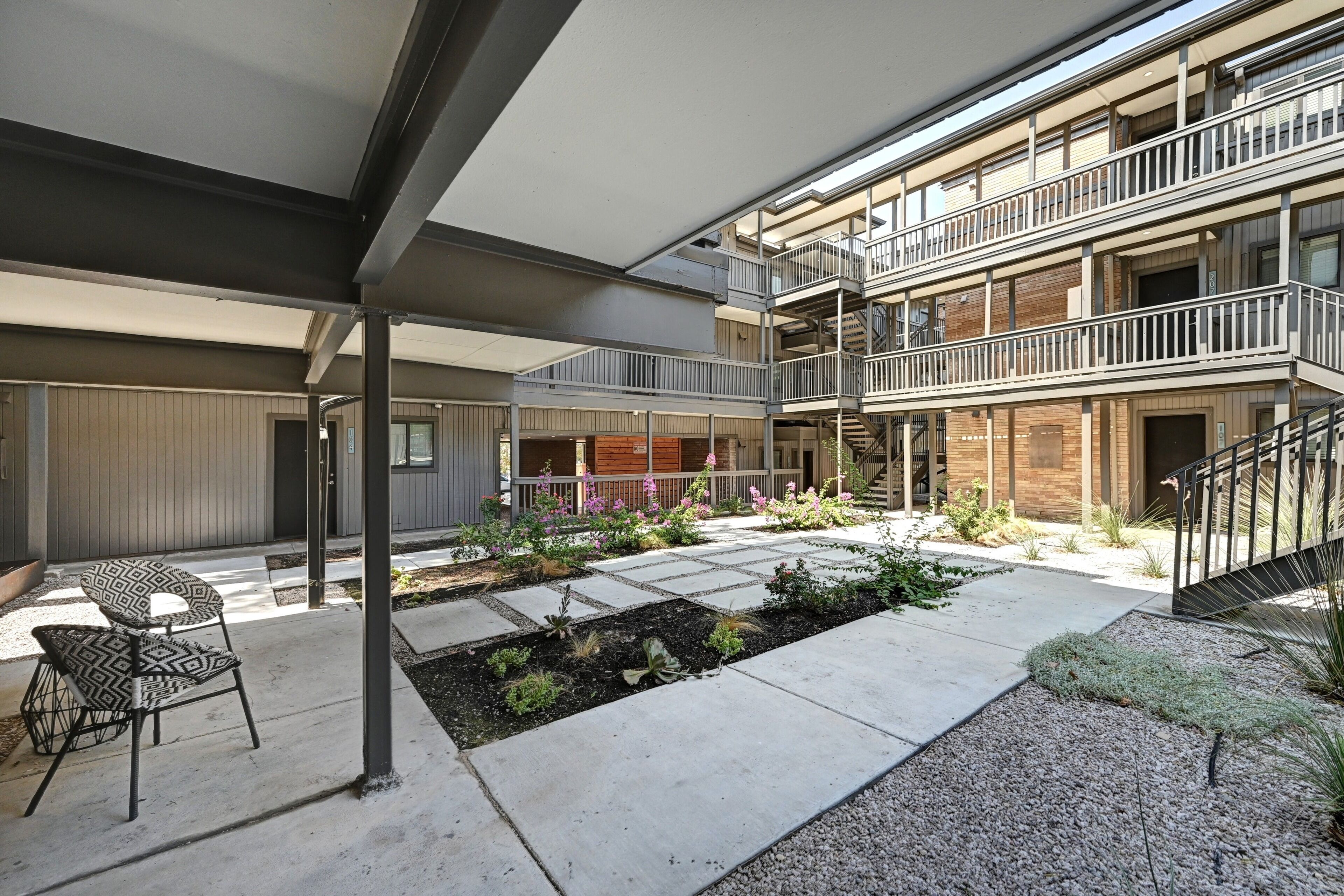 A multi-level outdoor area with a covered seating area, a landscaped garden, and a staircase leading to an upper level.