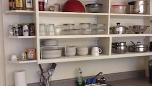 Una cucina con mobili bianchi, un piano di lavoro in granito e diversi oggetti, tra cui stoviglie, pentole e bottiglie.