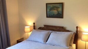 Un letto ben rifatto con due cuscini, una testiera in legno e un quadro incorniciato sopra.
