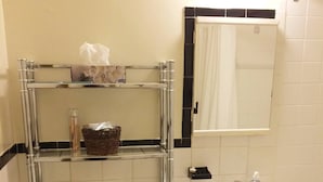 Un bagno con WC, lavandino e specchio. Si vedono scaffali con articoli da toilette e un cesto.