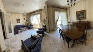 Een ruime woonkamer met een grote ronde tafel, een bank en een eethoek.