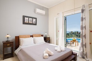 A bedroom with a bed, a nightstand, a lamp, a picture frame, and a view of a pool and outdoor seating.