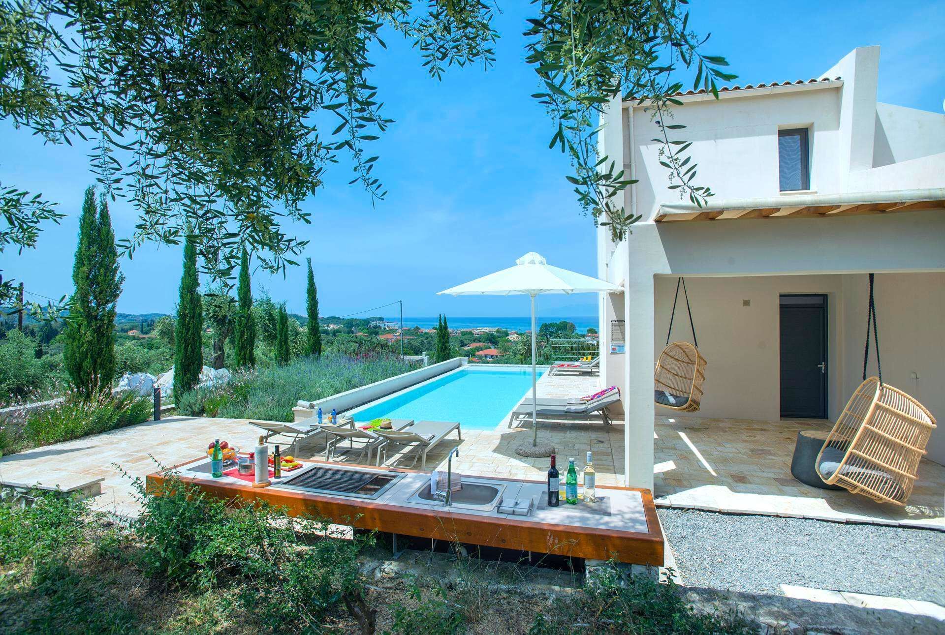A modern villa with a swimming pool, outdoor seating, and a view of the sea.