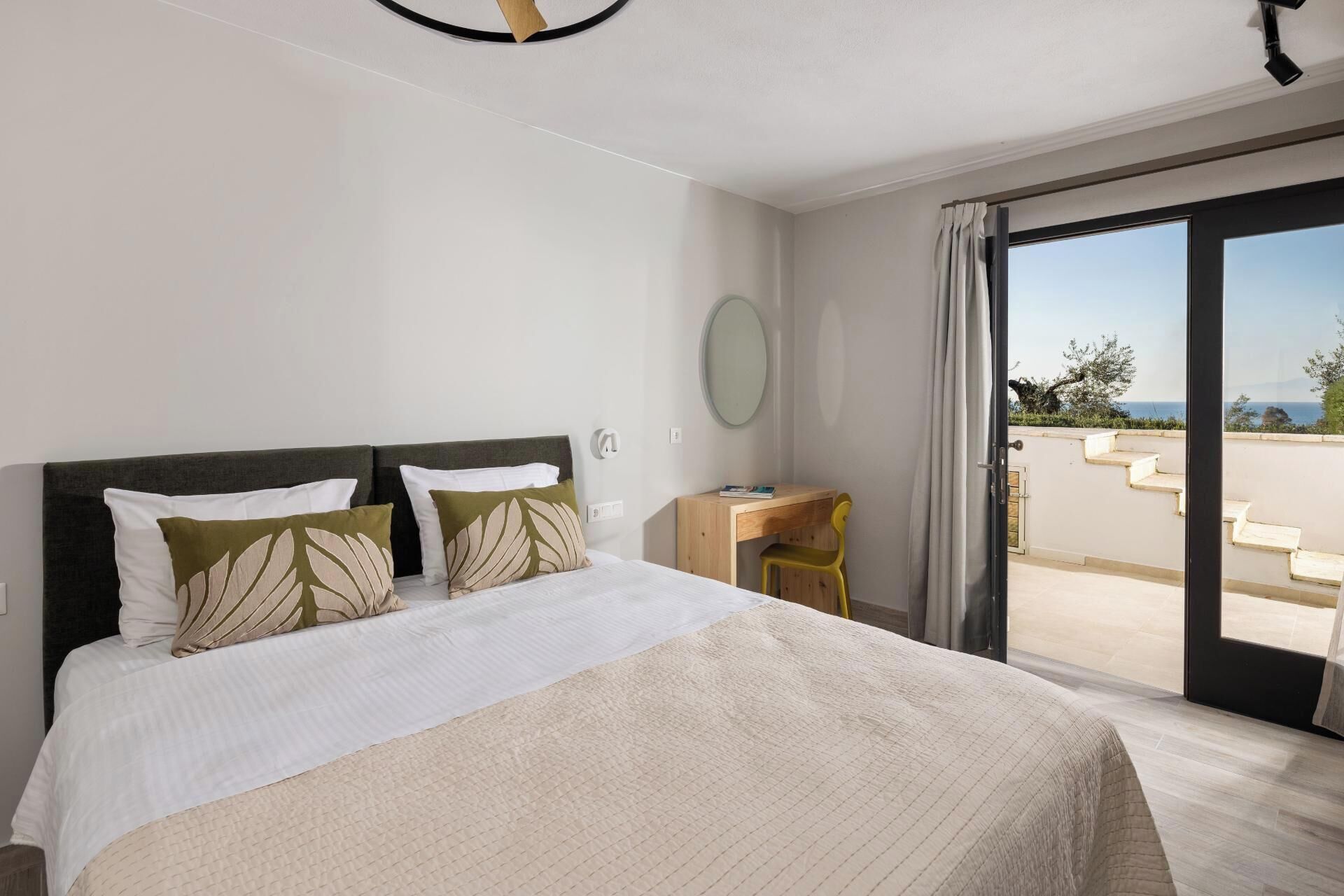 Een slaapkamer met een bed, een bureau, een stoel, een raam en uitzicht op de omgeving.