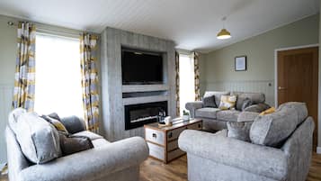 A living room with a fireplace, two grey sofas, a coffee table, and patterned curtains.