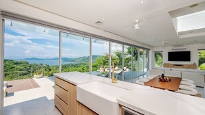 Una cocina moderna con una isla grande, un comedor y vistas a un paisaje exuberante.