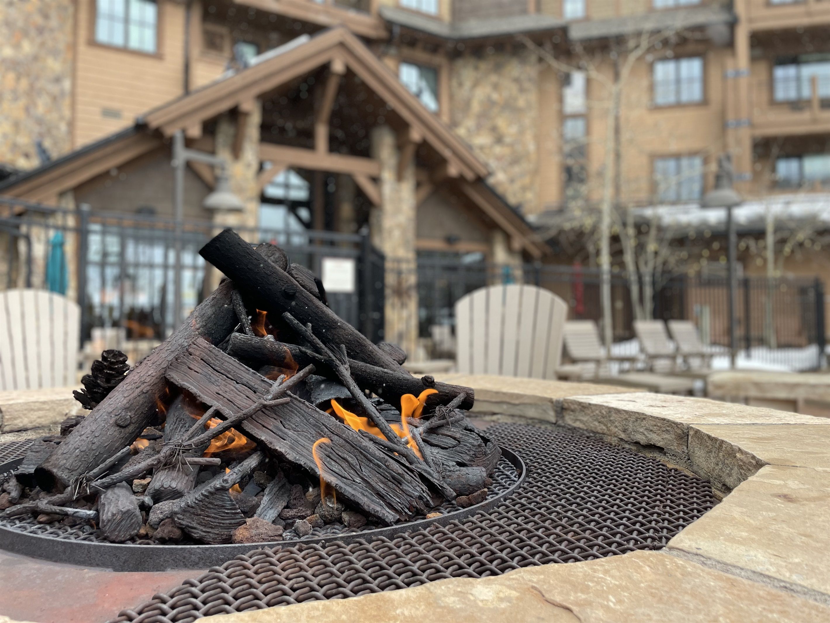 A fire pit with logs and embers, surrounded by stone seating.