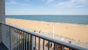 Vista de la playa desde un balcón con barandilla, una playa de arena y el océano.