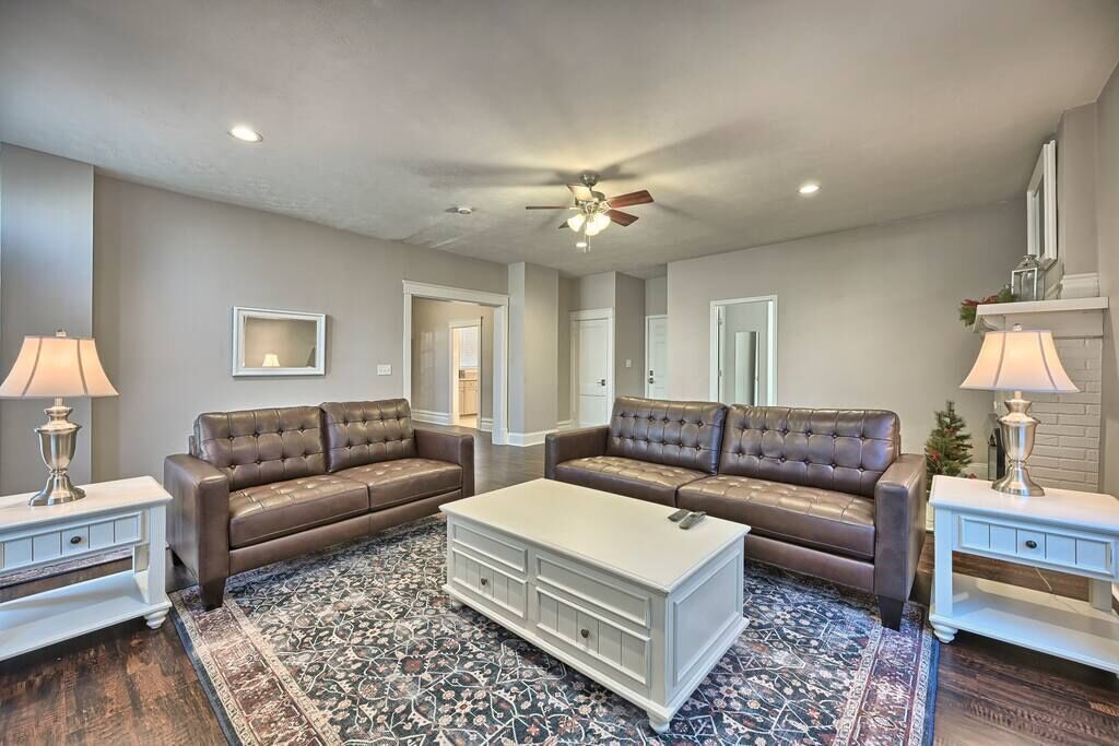 A living room with two brown leather sofas, a white coffee table, and patterned rugs.